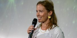 Eine Frau, die ein Mikrofon in der Hand hält und lächelt. 