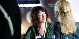 Eine Gesprächssituation an einem Tisch, bei der zwei Frauen einander zugewandt im Austausch stehen.