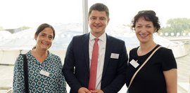 Ein Mann steht zwischen zwei Frauen, alle drei lächeln in die Kamera.