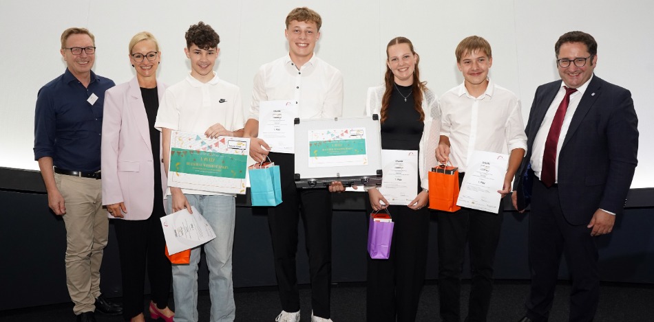 Eine Gruppe von sieben Personen, von denen fünf Zertifikate und Geschenke halten, posiert für ein Foto.