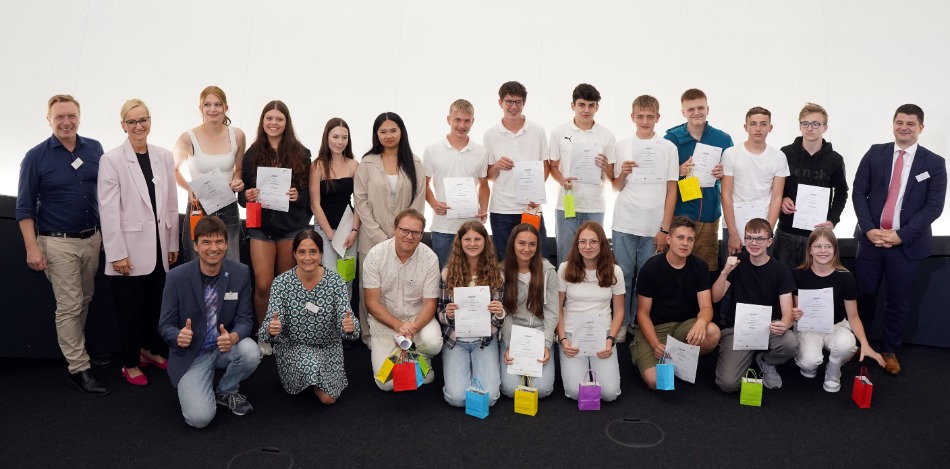 Eine Gruppe aus Erwachsenen und Schülern, die Plakate hochhalten, posieren für ein Bild