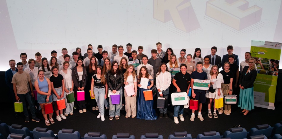 Eine Gruppe von Menschen posiert für ein Foto. Einige Personen halten Zertifikate, andere bunte Geschenktüten. 