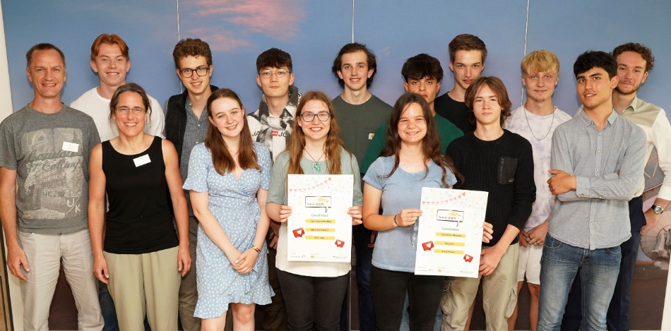 Eine Gruppe Schüler, die Plakate in der Hand halten und mit zwei Erwachsenen für ein Foto posieren