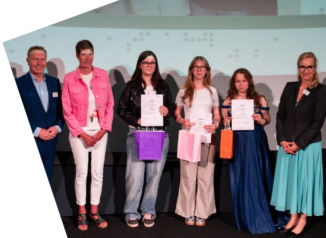 Drei Schülerinnen, die Plakate in der Hand halten und mit drei Erwachsenen für ein Foto posieren