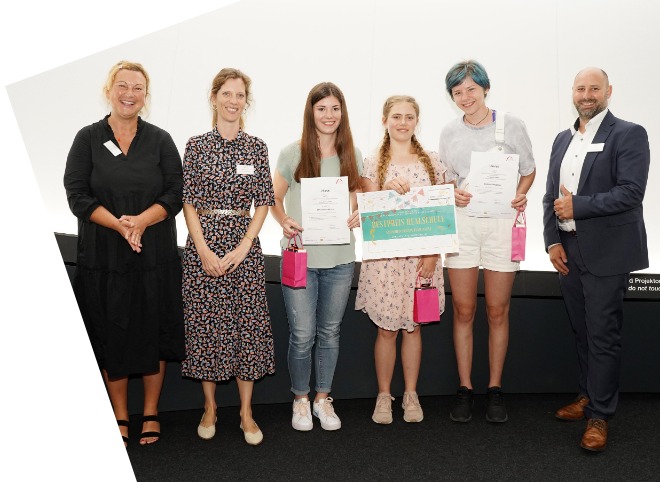 Die Gewinner des Bestpreises der Realschulen Zwei Schülerinnen, die Plakate in der Hand halten und mit vier Erwachsenen für ein Foto posieren