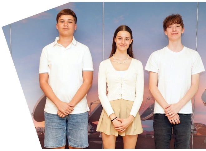 Abschlussveranstaltung 2023 Zwei Schüler und eine Schülerin, vor einer blauen Wand, die für ein Foto posieren