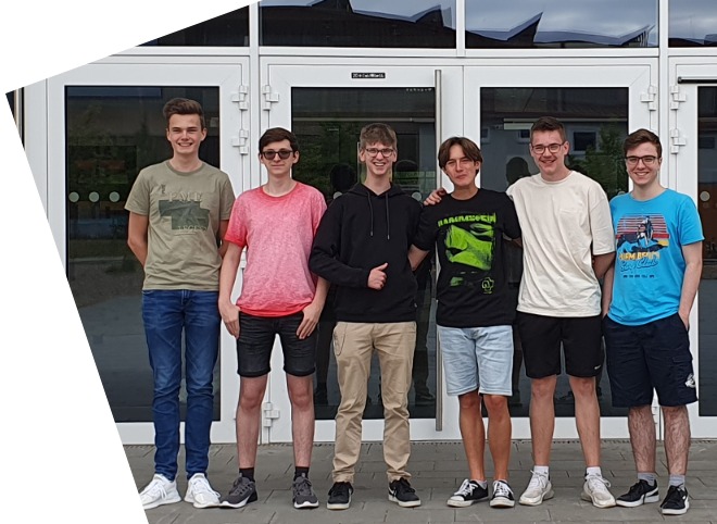 Abschlussveranstaltung 2023 Sechs Schüler, vor einem Gebäude, die für ein Foto posieren