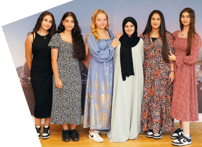Abschlussveranstaltung 2023 Sechs Schülerinnen, vor einer blauen Wand, die für ein Foto posieren