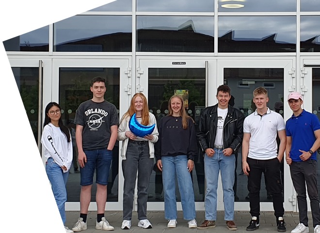 Abschlussveranstaltung 2023 Drei Schülerinnen und vier Schüler, vor einem Gebäude, die für ein Foto posieren