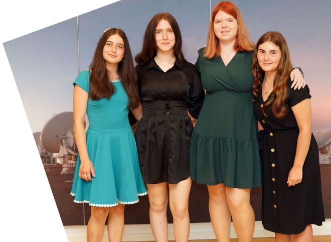 Abschlussveranstaltung 2023 Vier Schülerinnen, vor einer blauen Wand, die für ein Foto posieren