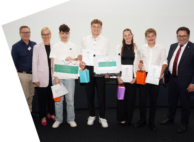 Abschlussveranstaltung 2024 Vier Schüler, die Plakate in der Hand halten und mit drei Erwachsenen für ein Foto posieren