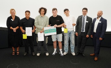 Die Gewinner des Bestpreises der Mittelschulen Vier Schüler, die Plakate in der Hand halten und mit drei Erwachsenen für ein Foto posieren