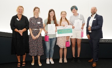 Die Gewinnerinnen des Bestpreises der Realschulen Zwei Schülerinnen, die Plakate in der Hand halten und mit vier Erwachsenen für ein Foto posieren