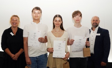 Die Gewinner des Blogpreises Zwei Schüler und eine Schülerin, die Plakate in der Hand halten und mit zwei Erwachsenen für ein Foto posieren