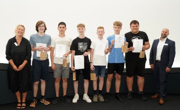Die Gewinner des Praxispreises Sechs Schüler, die Plakate in der Hand halten und mit zwei Erwachsenen für ein Foto posieren