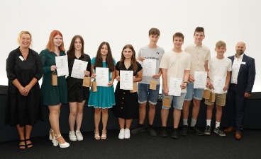 Die Gewinner des Zukunftspreises Eine Gruppe von Schülern, die Plakate in der Hand halten und mit zwei Erwachsenen für ein Foto posieren