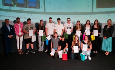 Eine Gruppe Schülerinnen und Schüler, die Plakate in der Hand halten und mit drei Erwachsenen für ein Foto posieren