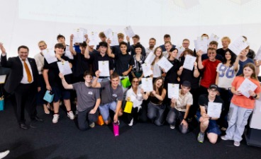 Eine Gruppe Schülerinnen und Schüler, die Plakate in der Hand halten und mit Erwachsenen für ein Foto posieren